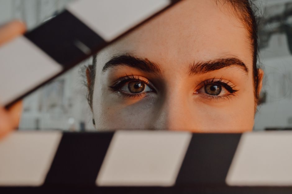 Intriguing close-up of a person's eyes behind a movie clapperboard, symbolizing filmmaking artistry.