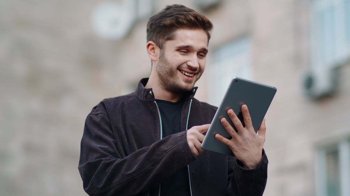 Director smiling at tablet showing synced cloud footage timeline